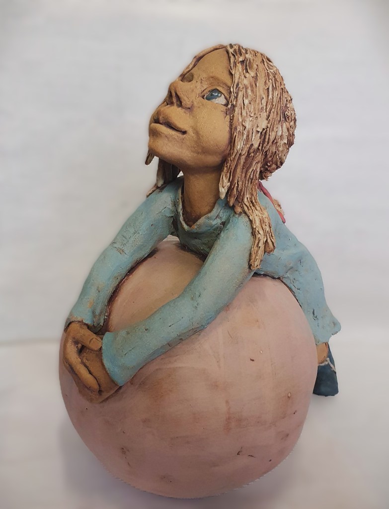 Meisje in keramiek, leunend op grote bal