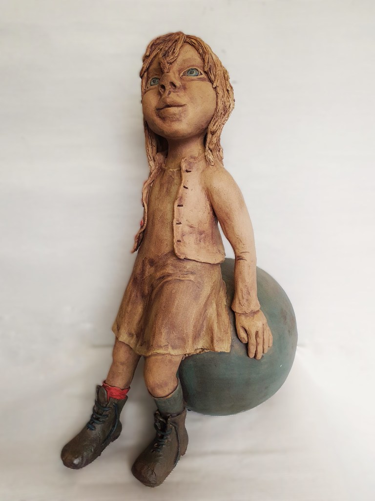 meisje met laarsjes op bal van klei.